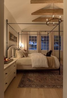 a bedroom with a canopy bed, dressers and rug on the floor in front of it