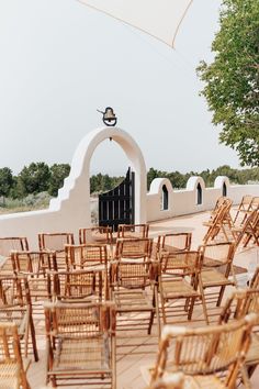 rows of wooden chairs sitting under an umbrella