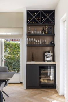 a dining room table with chairs and a wine rack on the back wall in front of a sliding glass door