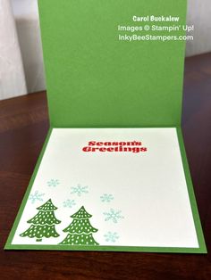 an open card with christmas trees and snowflakes on the inside, sitting on top of a wooden table