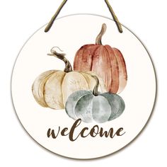 a welcome sign with three pumpkins on it