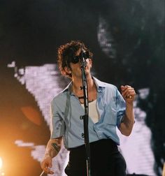 a man standing on top of a stage holding a microphone in his hand and singing