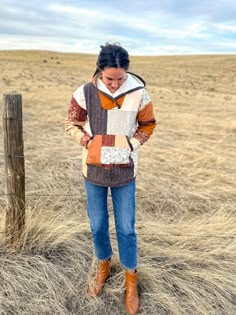 a woman standing on top of a dry grass covered field