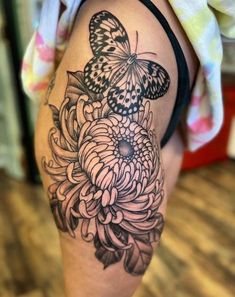 a woman's thigh with a butterfly and flower tattoo on the side of her leg