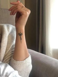 a woman's arm with a cross tattoo on it