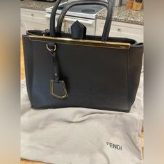 This Stunning 2jours Bag (26 Cm X 36 Cm X 16 Cm) Features Textured Leather On The Body, A Sleek Logo Top Bar, A Matching Luggage Tag, Two Toting Handles And A Detachable Shoulder Strap. The Dual Interior Compartments With A Center Zip Compartment Make It Ideal For Holding Your Daily Essentials. Carry This Beauty On Your Arm For An Instantly Chic Look, You Don't Want To Miss Out On This Current And Gorgeous Piece From Fendi! Current Retail Price Is $2350. From Fendi's Current Collection, This Gor Sleek Logo, Bar Top, Daily Essentials, Luggage Tag, Luggage Tags, To Miss, Womens Tote Bags, Fendi, Shoulder Strap