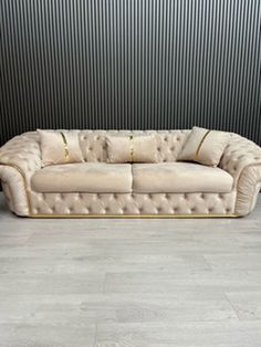 a beige couch sitting on top of a wooden floor next to a black and white wall