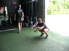 two men in a gym with one holding a baseball bat and the other squatting down