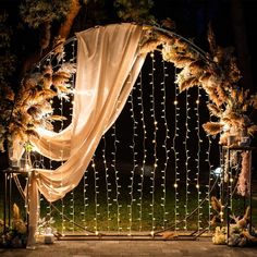 a wedding arch decorated with lights and feathers