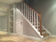 an empty room with stairs and bookcases on the wall next to the door