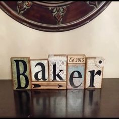 wooden blocks spelling the word baker on top of a black table next to a mirror