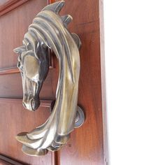 a horse head is mounted to the side of a wooden door with a metal handle