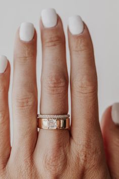 a woman's hand with white nails and a gold ring on her left hand