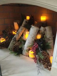 candles and pine cones are on display in the fireplace