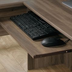 a computer keyboard sitting on top of a wooden desk next to a mouse and monitor