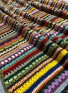 a multicolored crocheted blanket laying on top of a bed