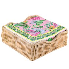 a wicker box with a pink and green floral design on the lid, sitting on a white background