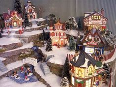 a christmas village with lights and snow on the ground