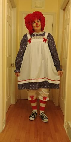 a woman with red hair wearing a white dress and striped socks standing in a hallway