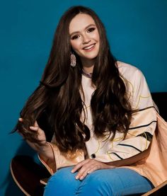 a woman with long hair sitting on a chair