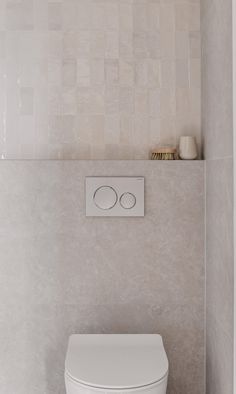 a white toilet sitting in a bathroom next to a wall mounted faucet with two circles on it