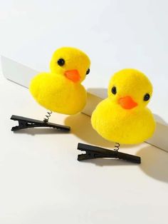 two yellow rubber ducks sitting on top of a pair of black hair clippers next to each other