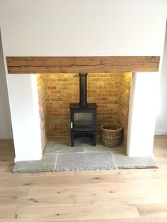 an old fashioned stove in the corner of a room with wood flooring and white walls