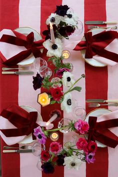 the table is set with red and white striped linens, silverware, candles, and flowers