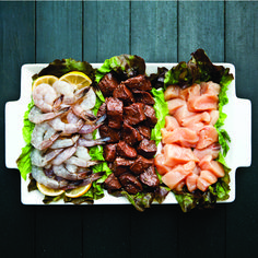 an assortment of meats and vegetables on a platter with lettuce leaves