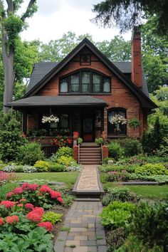 a brick house with lots of flowers in the front yard and steps leading up to it