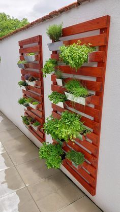 a vertical garden on the side of a building with wooden slats and plants growing in them