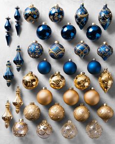 an assortment of blue and gold christmas ornaments on a table with white background, top view