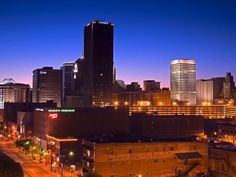 the city skyline is lit up at night with lights on and buildings in the background