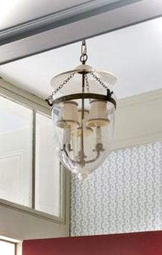 a chandelier hanging from the ceiling in a room with red and white wallpaper