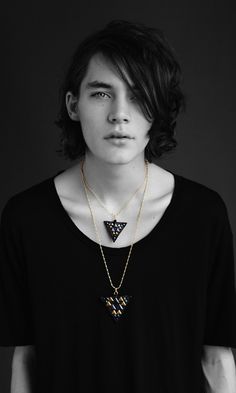 a young man wearing a black shirt and necklace