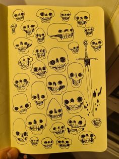 a hand holding up a yellow notebook with skulls on it