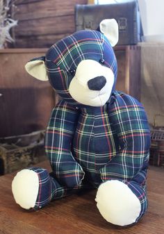 a blue and green plaid teddy bear sitting on top of a wooden table next to an old trunk