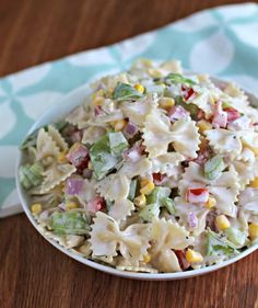 a white bowl filled with pasta salad on top of a wooden table next to a blue and white towel