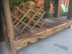 a wooden bench made out of wood with vines on the bottom and sides, sitting in front of a building