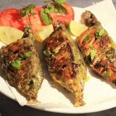 three pieces of fish on a plate with tomatoes and lemons