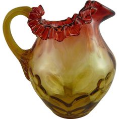 a brown and yellow glass vase with red flowers on the top, sitting in front of a white background