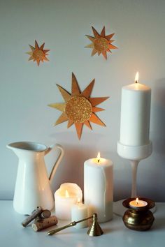 candles, tea light holders and other items are arranged on a white countertop with gold stars above them