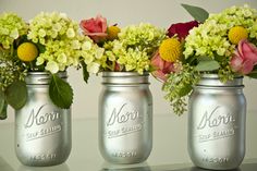 two mason jars with flowers in them sitting on a table