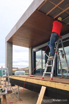 a man standing on top of a ladder next to a building