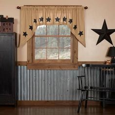 a window with black stars hanging from it's side and a wooden dresser in the background