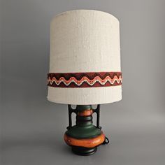 a lamp that is sitting on top of a table next to a light fixture with a white shade over it