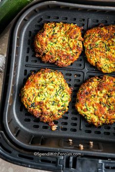 four crab cakes in a grill pan with zucchini on the side