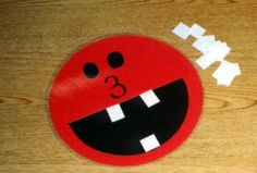 a close up of a red smiley face on a wooden surface with cut out letters