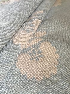 a close up view of the fabric on a bed with white and blue flowers in it