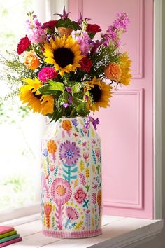 a vase filled with lots of flowers sitting on top of a window sill next to a pink door